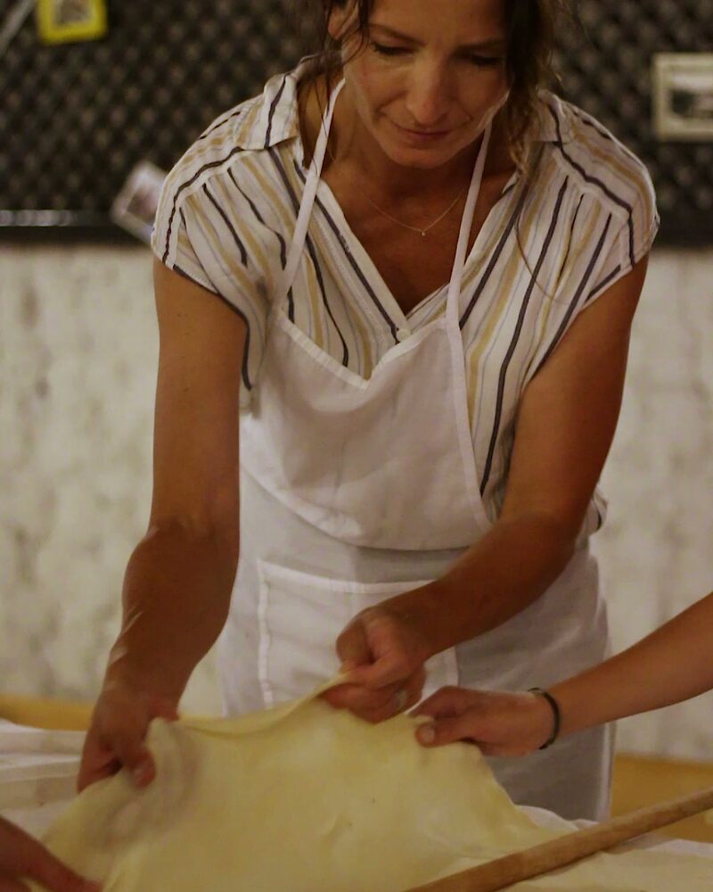 Guest stretching thin burek dough during a Burek Masterclass in Mostar